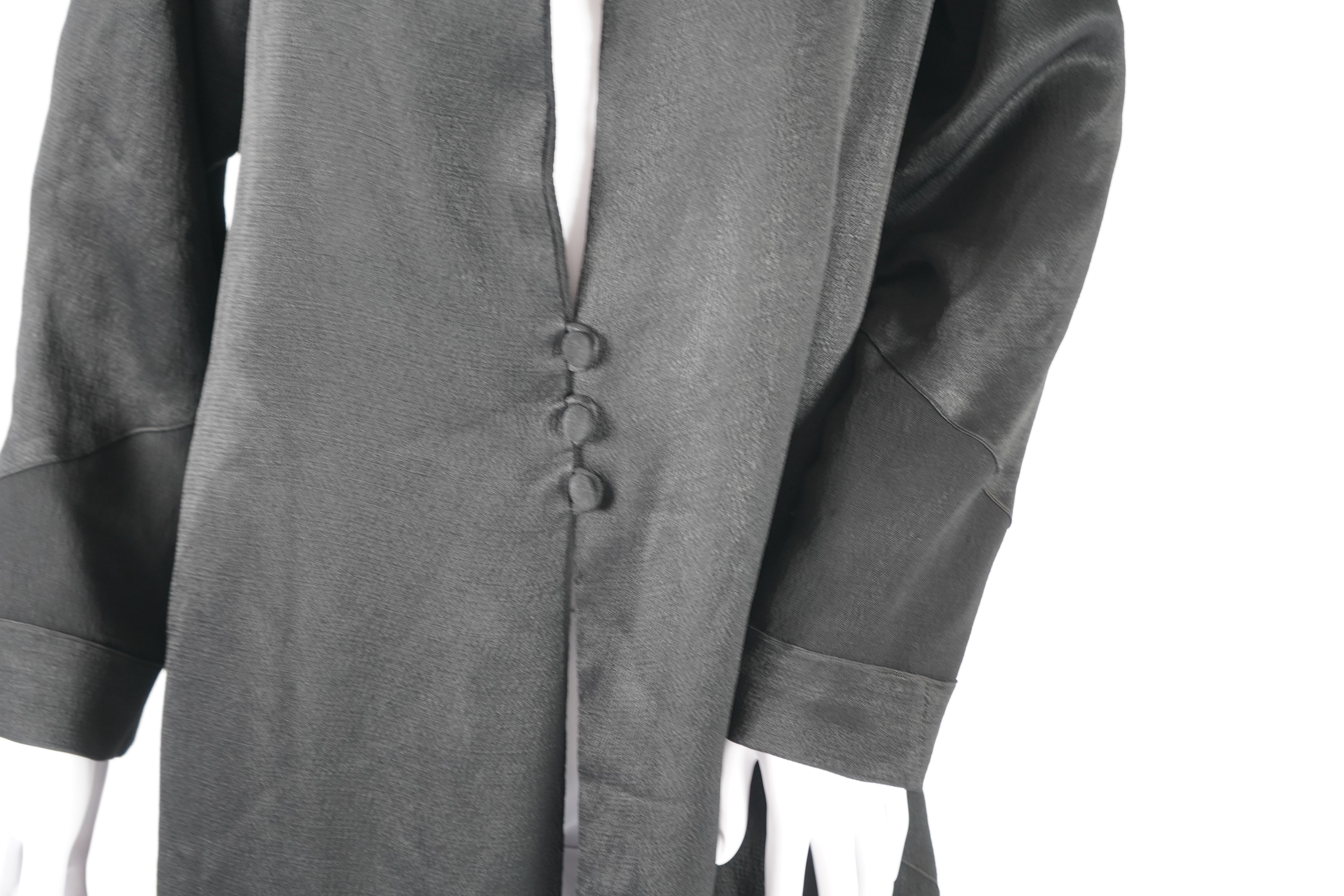 A 1930's black satin evening coat, with small collar and covered buttons to the front. Decorated with chevron motifs at side and lower sleeve detailing, front under arm width 19 inches, length back: top of collar to bott